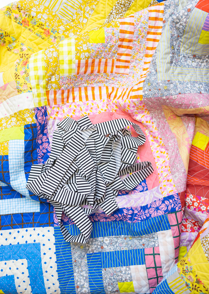 a colourful log cabin quilt and a bundle of quilt binding