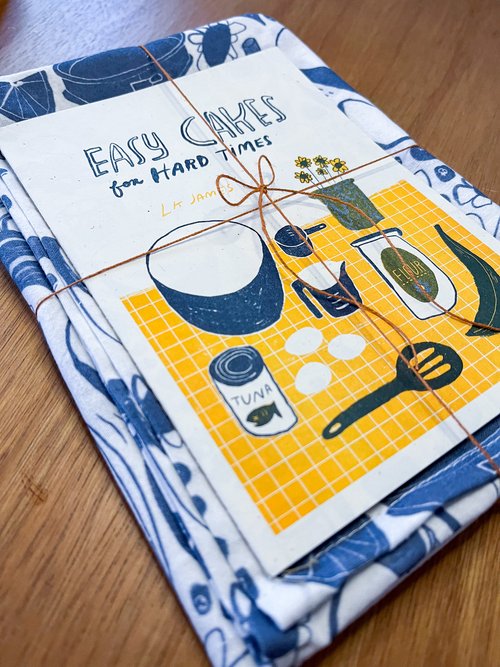 A teatowel and a zine titled Easy Cakes for Hard Times, bundled together with twine.