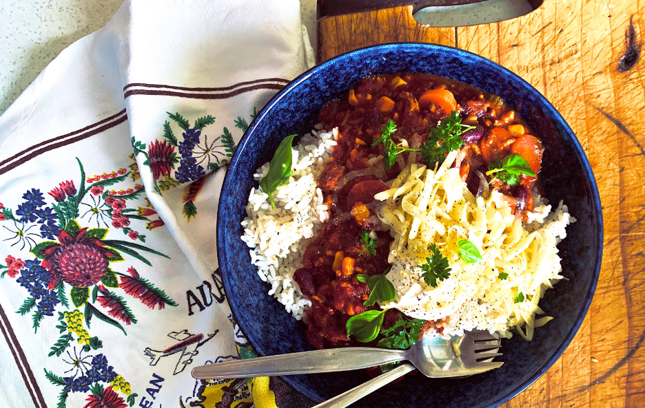 A bowl of chilli con carne beside a tea towel