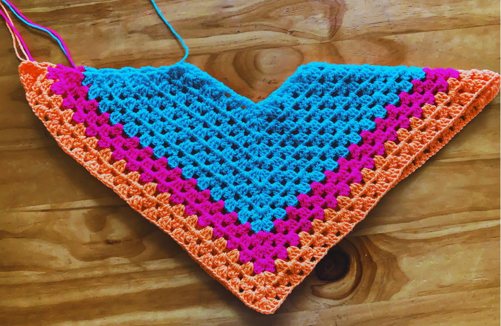 An in progress blue, pink and orange crochet poncho for June