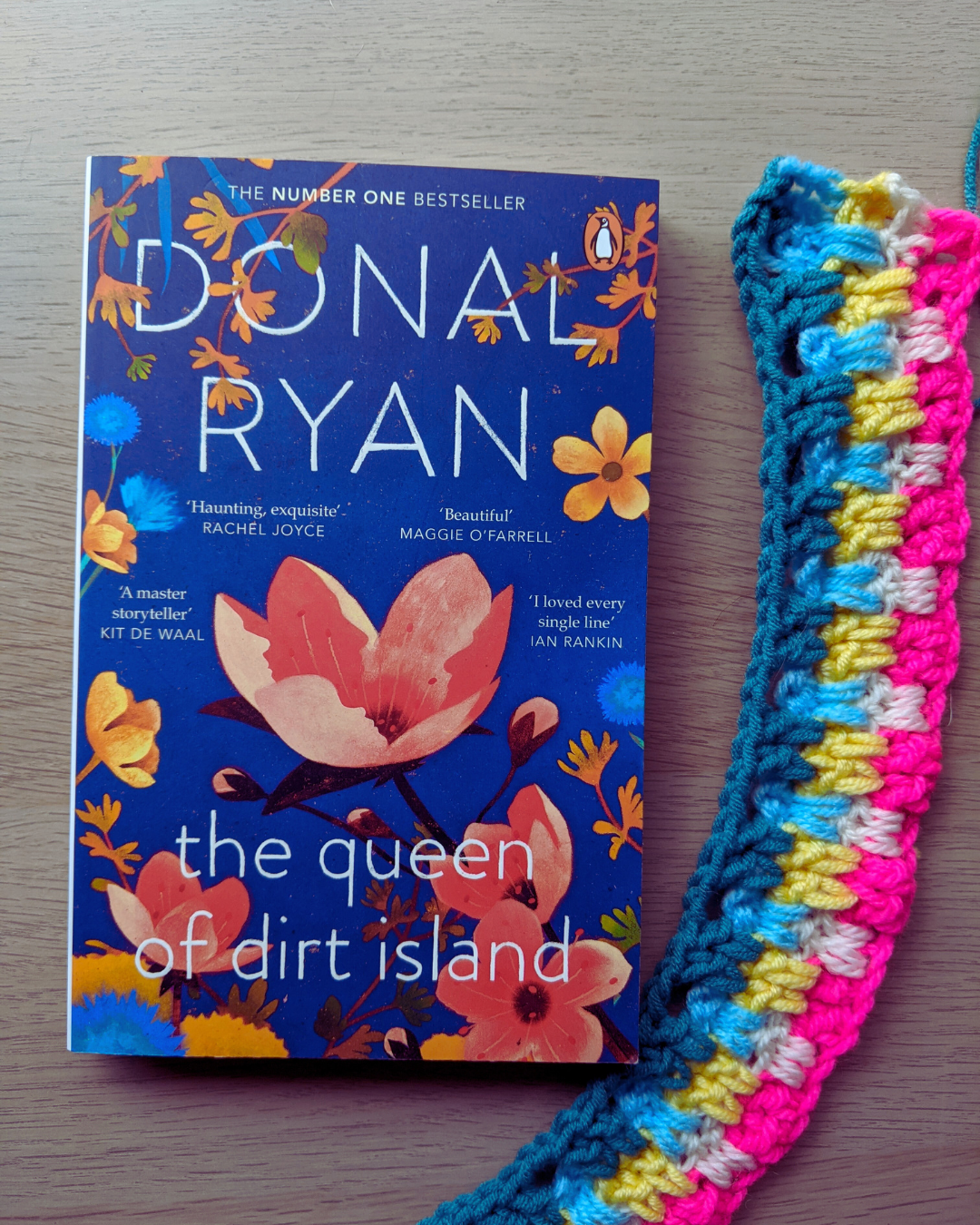 Image shows The Queen of Dirt Island book and some colourful crochet in Snuggle Stitch