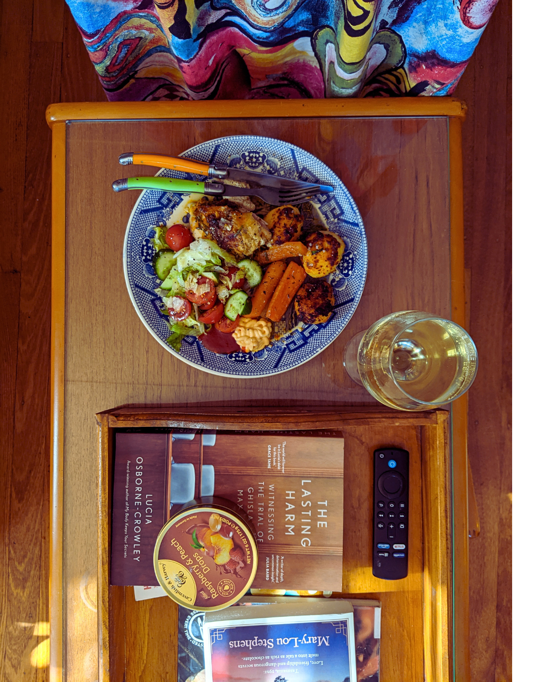 Roast chicken dinner alongside a glass of wine, paperback book and tin of travel sweets
